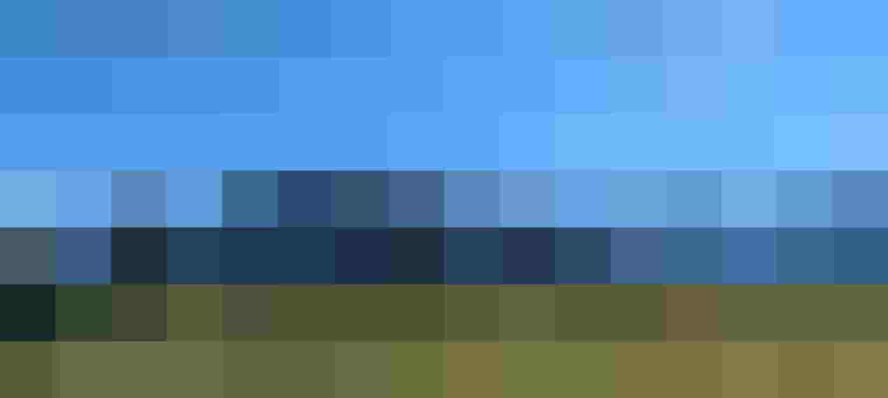 Grüne Wiese mit einzelnem Baum vor Alpenpanorama und blauem Himmel